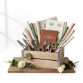Wooden crate filled with professional florist tools, wrapping paper, and a manual on a workbench